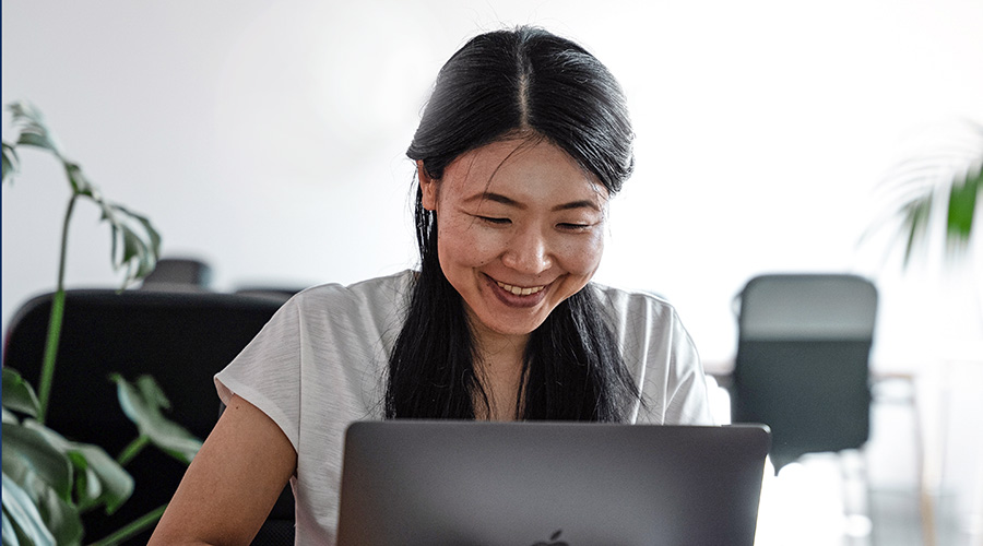 Asian woman at a laptop smiling