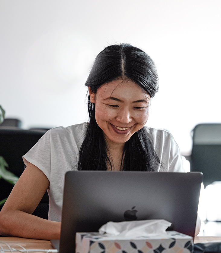 Asian woman at a laptop smiling